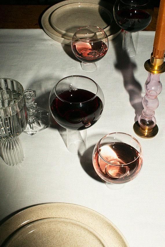 Photograph of a table with wine glasses, a candle, on a white tablecloth...